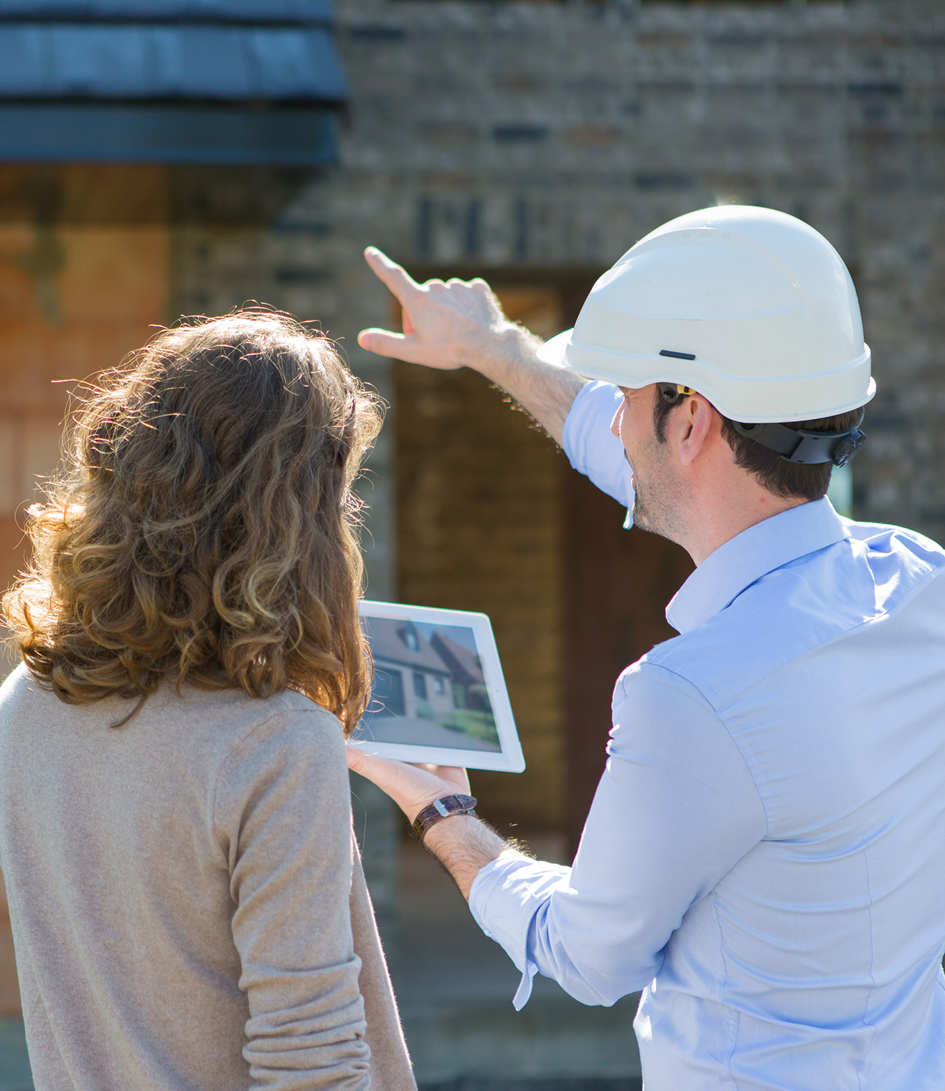 Architect and home studying plans infront of home